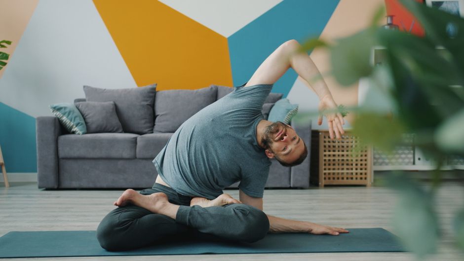 Étirement des ischio-jambiers au sol sur un tapis, dans un salon