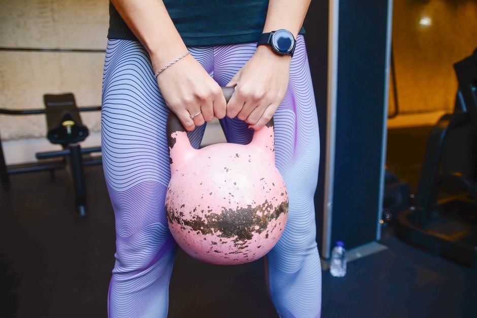 Gros plan sur une main qui tient la poignée d'une kettlebell, à l'intérieur