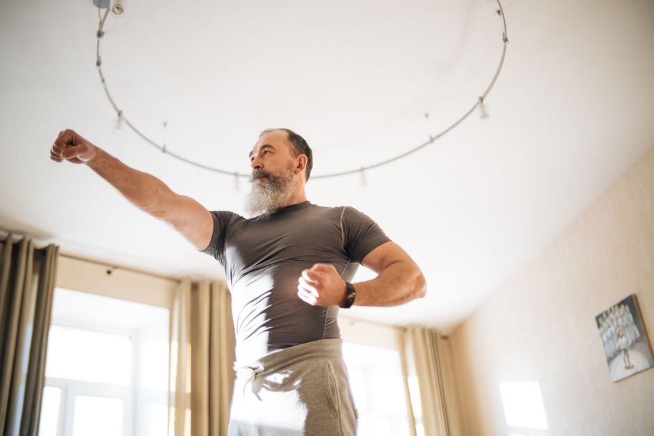 Homme réalisant un étirement d'épaule bras croisé dans un salon