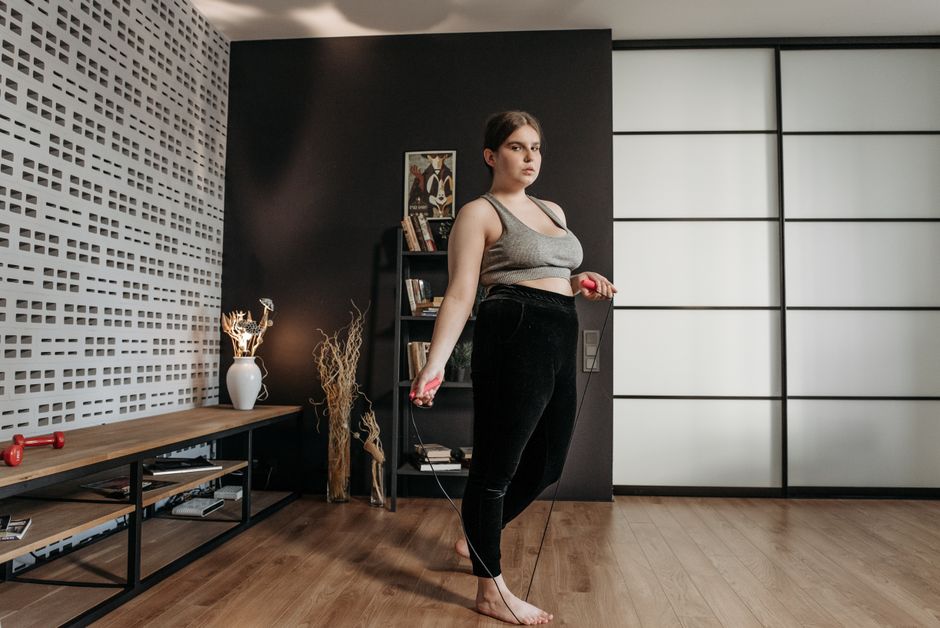 Personne sautant à la corde à câble acier dans un salon, parquet clair