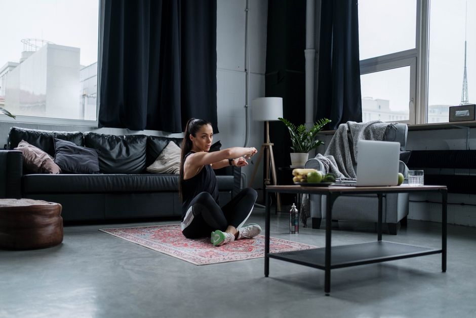 Femme en plein burpee dans un salon d'appartement, séance HIIT sans matériel