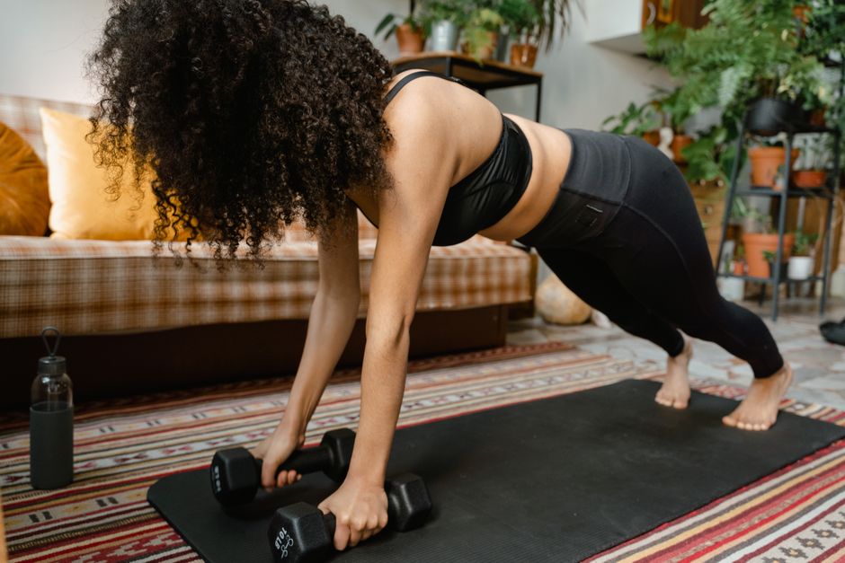 Personne en position de front squat, haltères sur les épaules, coudes hauts, dans un salon