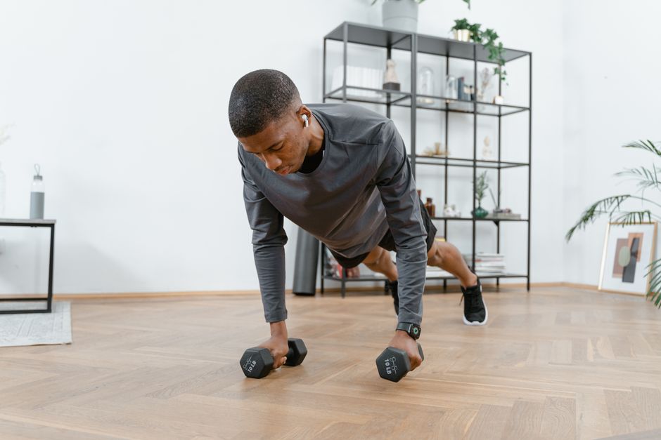 Pratiquant en position de planche au sol pendant un burpee, dans un salon lumineux