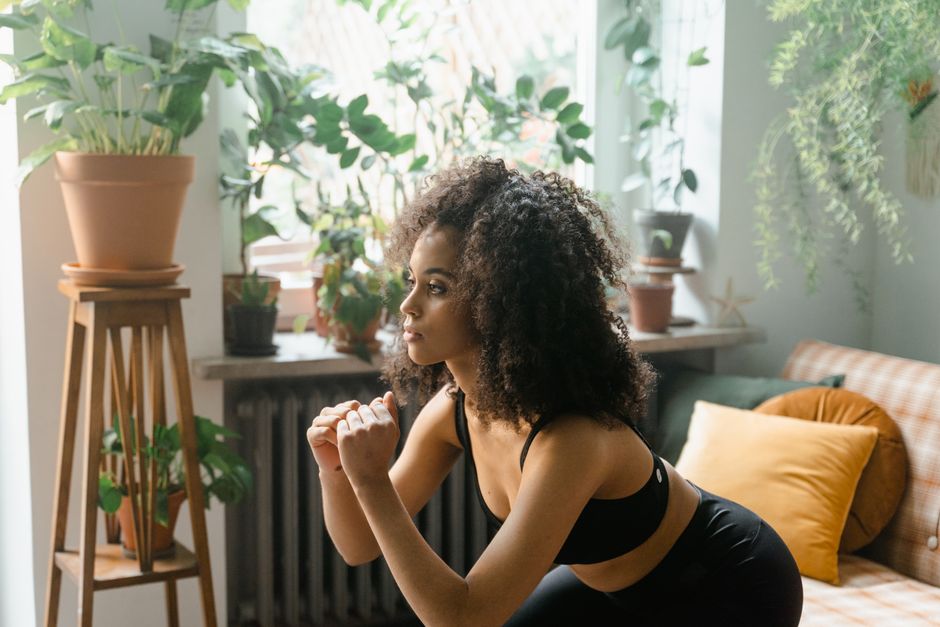 Femme en appartement enchaînant un squat dans un circuit training sans matériel