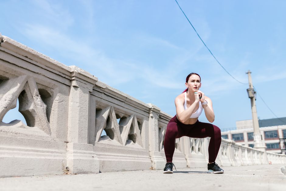 Femme en reprise du sport faisant des squats au poids du corps dans son salon