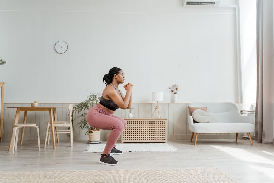 Squat bulgare exécuté au salon avec le canapé comme support, jambe arrière surélevée