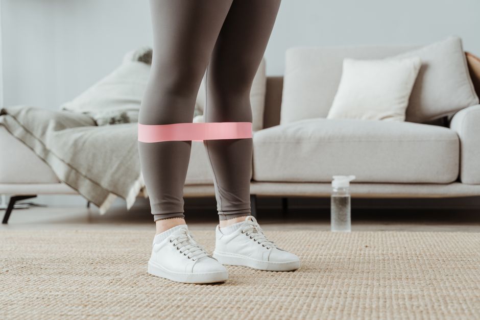 Set d'élastiques de musculation à code couleur posés sur un tapis de sol, ancrage de porte visible